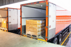 Package Boxes Loading into Cargo Container. Trailer Truck Parked Loading at Dock Warehouse. Delivery Service. Shipping Warehouse Logistics. Cargo Shipment Boxes. Freight Truck Transportation.